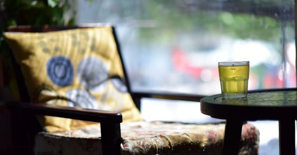 A cozy cafe scene featuring an intricately decorated chair and a refreshing glass of iced tea on a table.